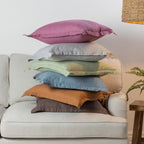 A vibrant collection of linen cushions in soft pastel and earthy tones is casually layered on a neutral sofa, bringing colour, natural texture and relaxed charm to a contemporary living space.