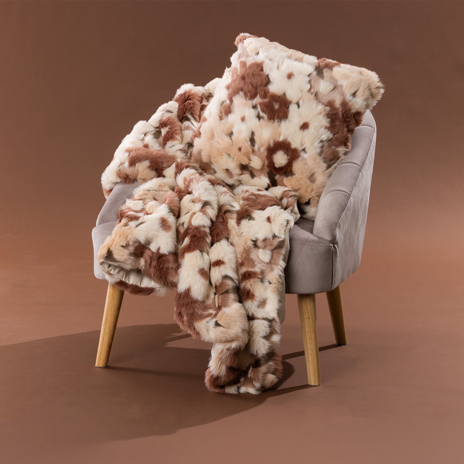 Amparo Macey Cushion in blush styled with the coordinating throw on a grey chair.