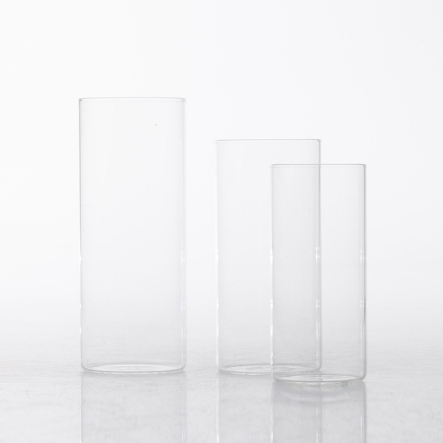 Set of clear glass cylinder vases displayed in varying heights on a white background.