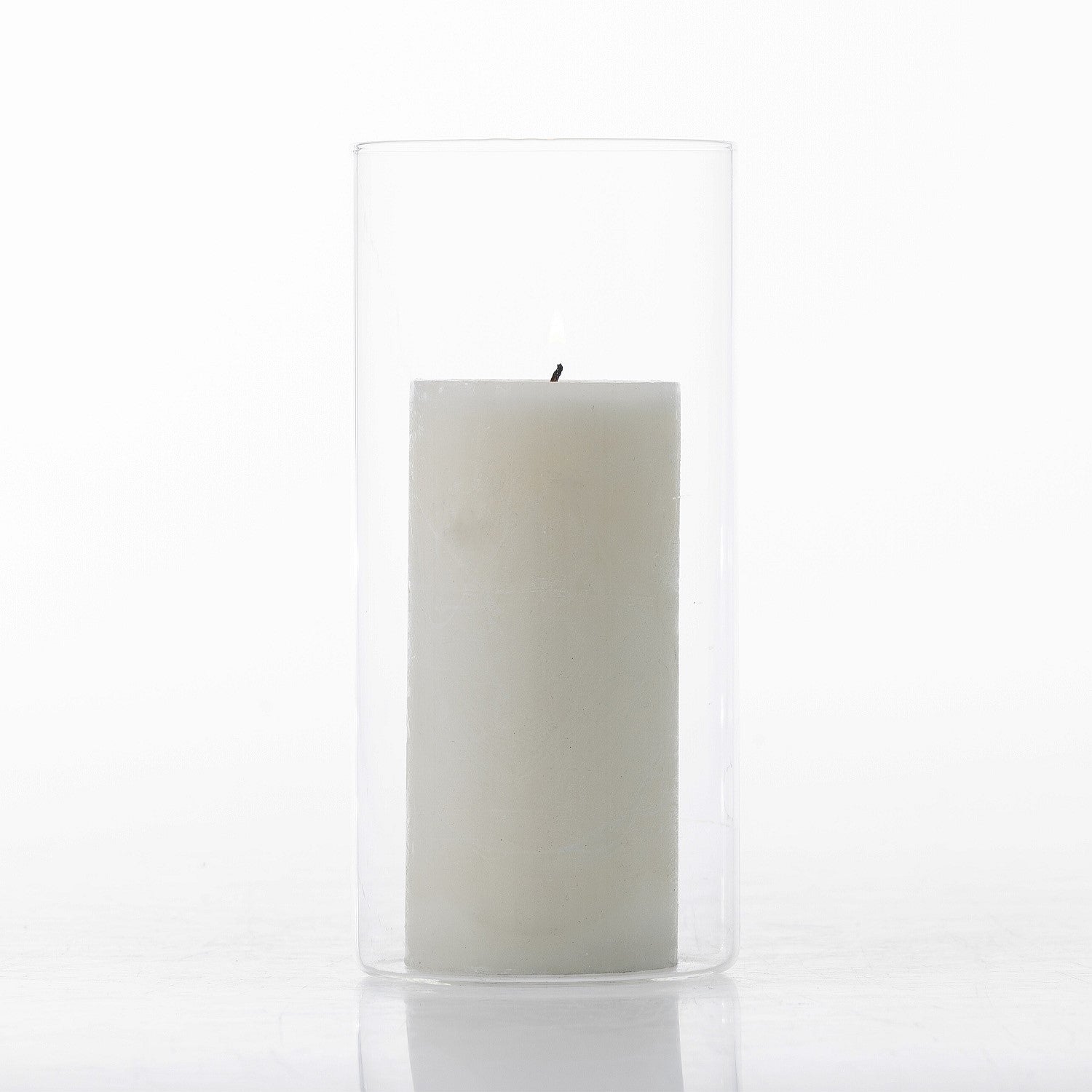 White pillar candle displayed inside a tall clear glass cylinder vase on a white background.