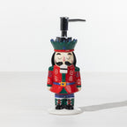 Christmas Wishes Nutcracker soap dispenser with red uniform, green crown and silver pump on a white background.