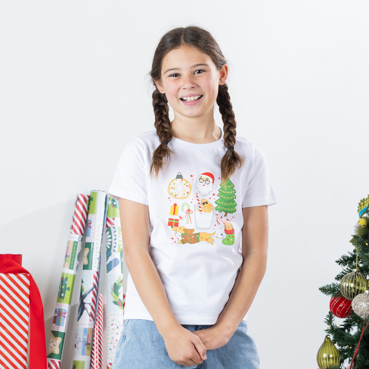 Girl wearing the Christmas Wishes Cheer Kids Tee in white, featuring a colourful festive Christmas character print on the front.
