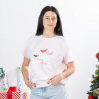 Front view of woman wearing the Christmas Wishes Merry Martinis Tee in pink, showing the relaxed short-sleeve fit and festive chest graphic.