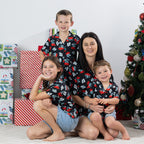 Family wearing matching black Christmas Wishes pōhutukawa festive shirts in a Christmas setting.