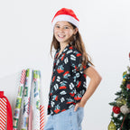 Girl wearing the black Christmas Wishes kids pōhutukawa festive shirt and a Santa hat.