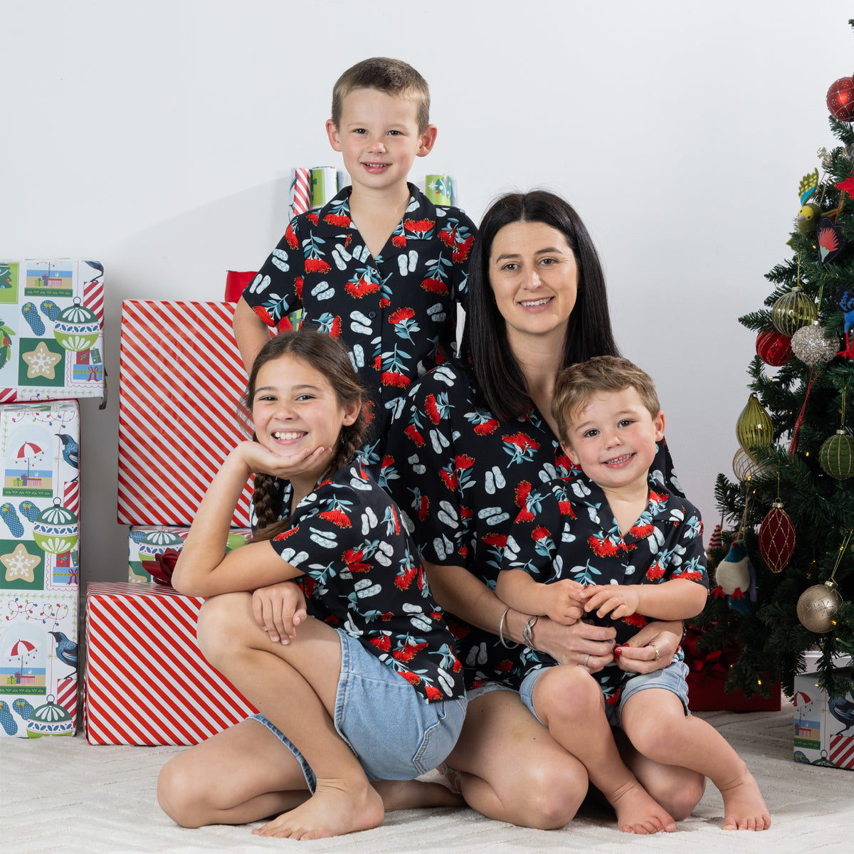 Family wearing matching black Christmas Wishes pōhutukawa festive shirts in a Christmas setting.