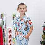 Young boy wearing the faded blue Christmas Wishes kids Cheeky Santa festive shirt with denim shorts.
