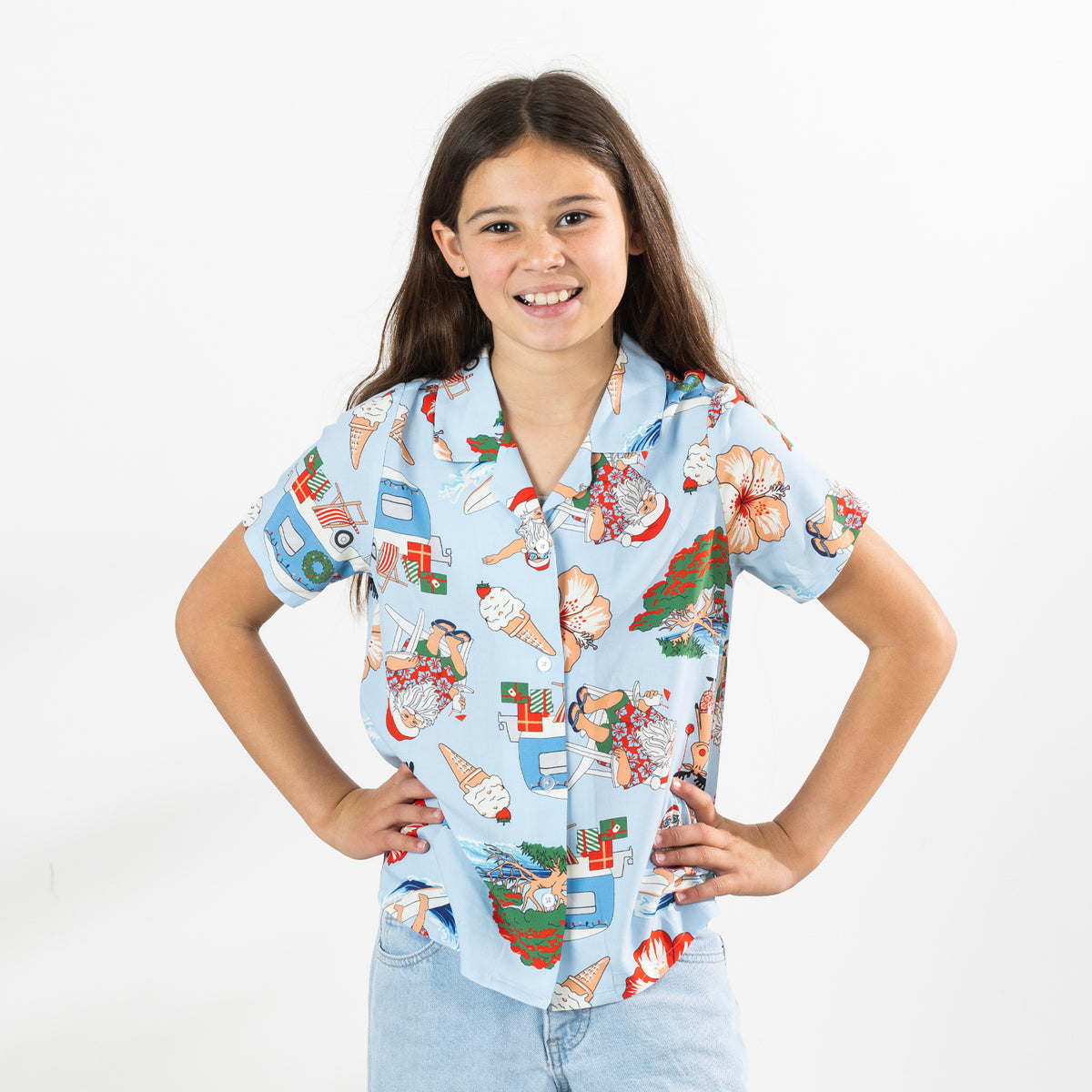 Girl wearing the faded blue Christmas Wishes kids Cheeky Santa festive shirt with light blue cargo pants.