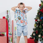 Young boy wearing the faded blue Christmas Wishes kids Cheeky Santa festive shirt in a playful Christmas setting.