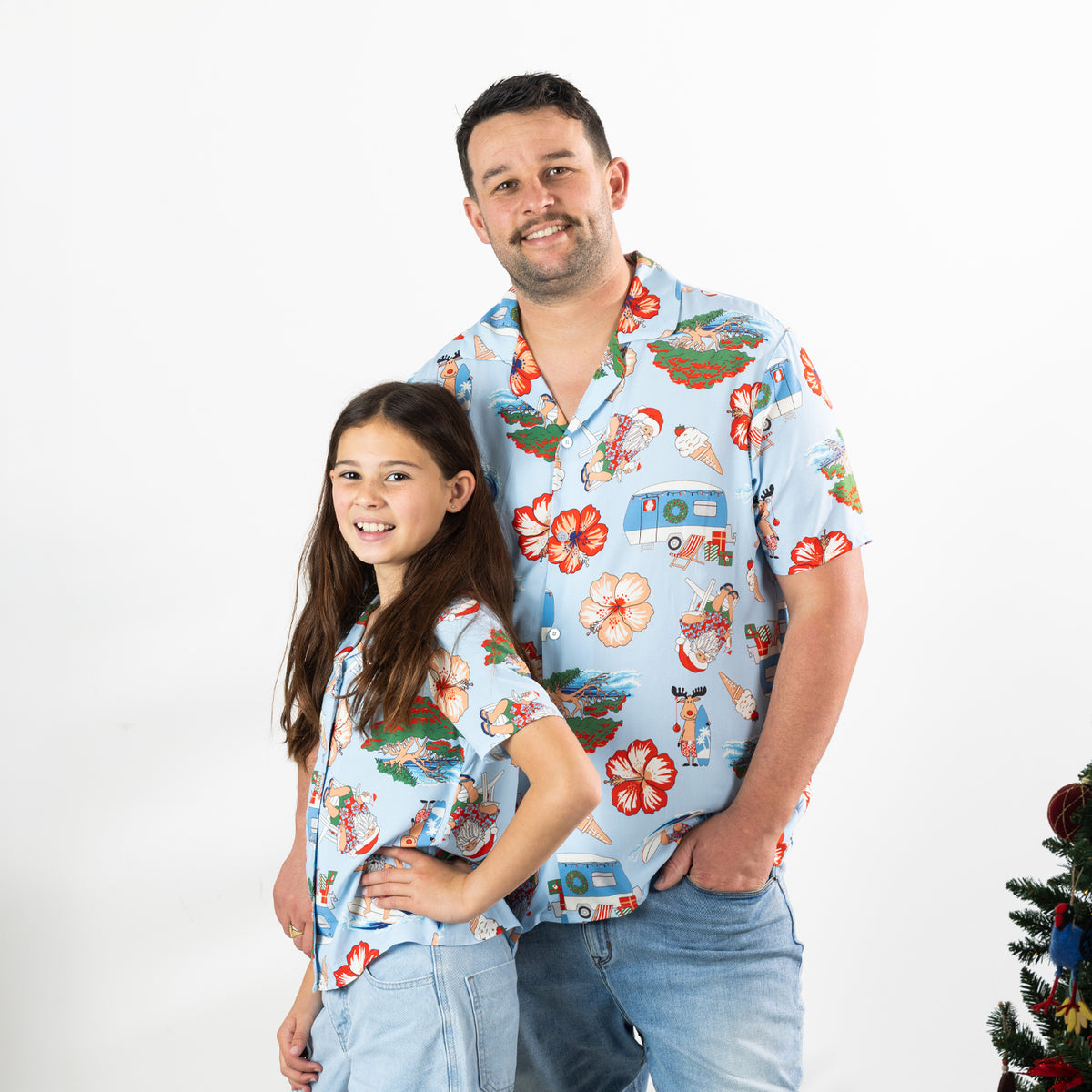 Man and girl wearing matching faded blue Christmas Wishes Cheeky Santa festive shirts.
