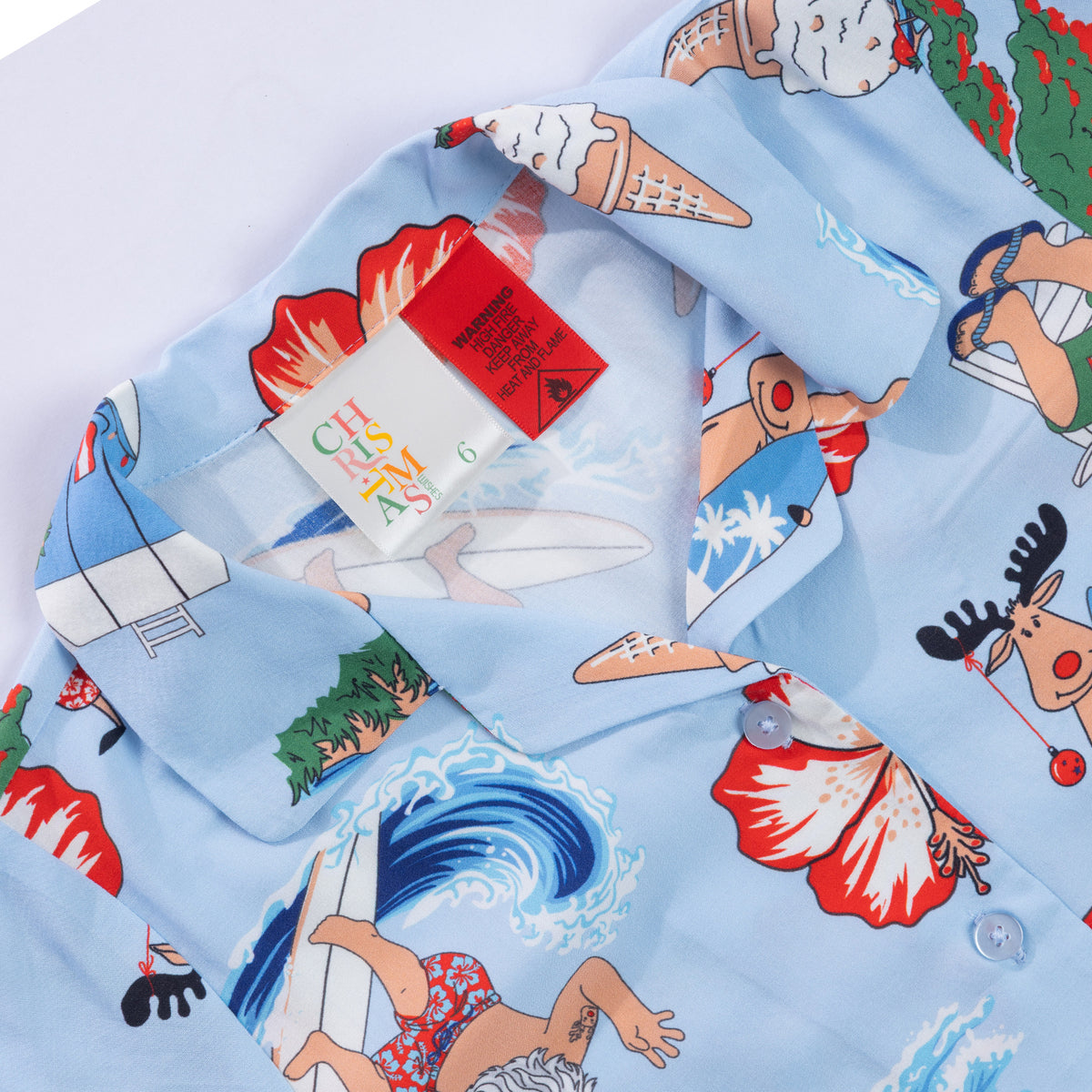 Close-up of the faded blue Christmas Wishes kids festive shirt collar and label, showing the colourful summer Christmas print.