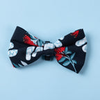 Close-up of the black festive dog bow tie featuring red pōhutukawa flowers and light blue jandals.