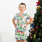 Boy wearing the Christmas Wishes Tui Kids PJ Set in white beside a decorated Christmas tree.