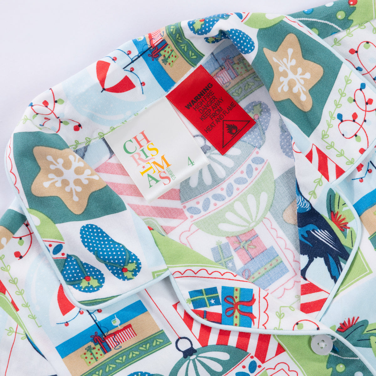 Close-up of the Christmas Wishes Tui Kids PJ Set collar, festive print, size label and safety warning tag.