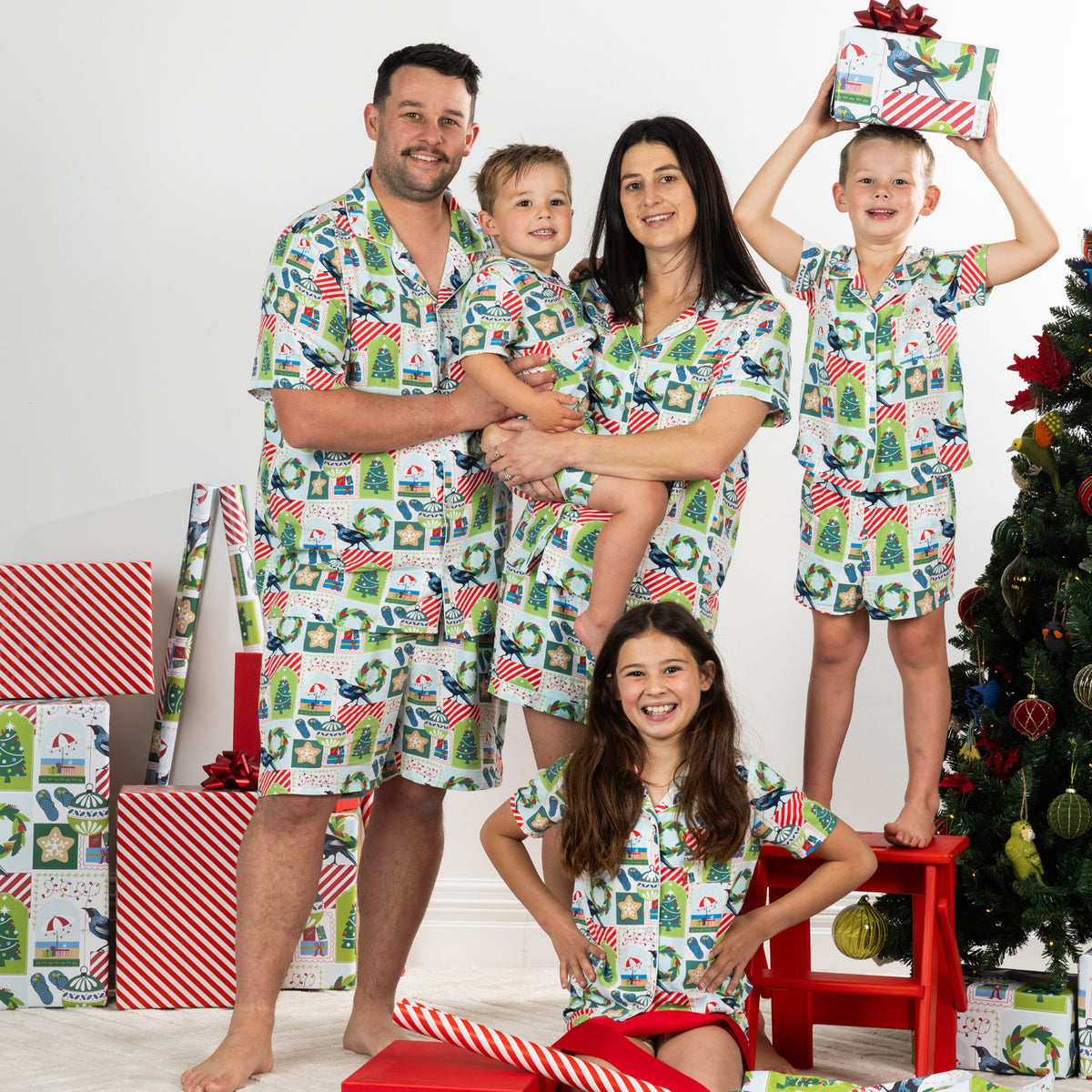 Family wearing matching Christmas Wishes Tui PJ Sets in white in a festive Christmas setting.