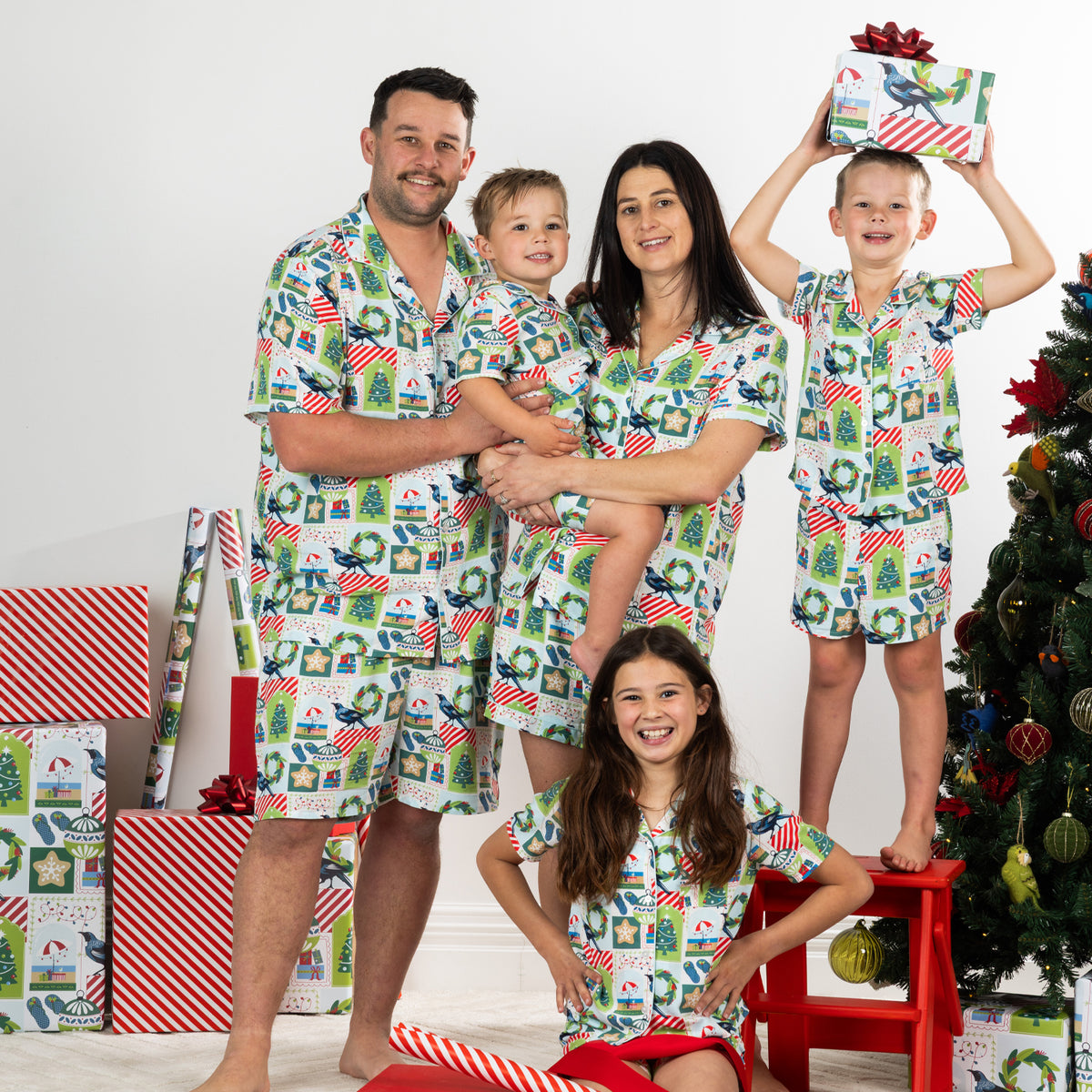 Family wearing matching Christmas Wishes Tui PJ Sets in white in a festive Christmas setting.