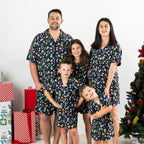 Family wearing matching Christmas Wishes Wreath PJ Sets in navy in a festive Christmas setting.
