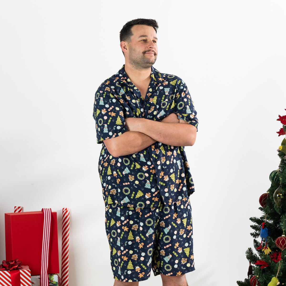 Man modelling the Christmas Wishes Wreath Men’s PJ Set in navy with arms crossed.