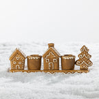 Gingerbread-style ceramic two-candle holder featuring festive houses and a Christmas tree with white icing-inspired detailing.