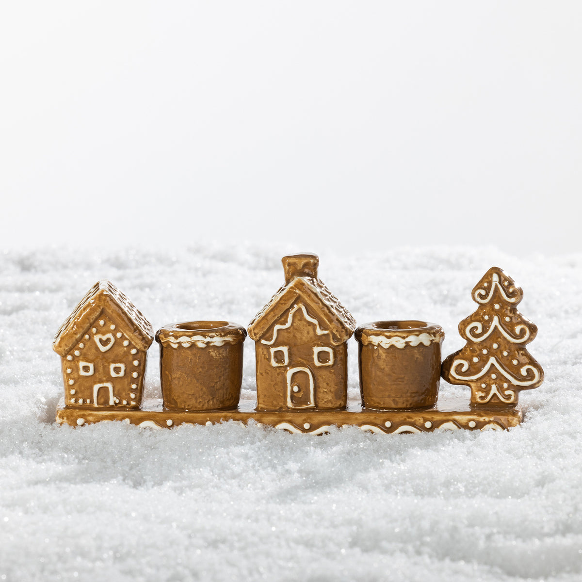 Gingerbread-style ceramic two-candle holder featuring festive houses and a Christmas tree with white icing-inspired detailing.
