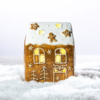 Gingerbread-style ceramic LED house displayed with coordinating gingerbread Christmas decorations in a snowy festive setting.