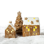 Gingerbread-style ceramic LED house displayed with coordinating gingerbread Christmas decorations in a snowy festive setting.