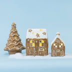 Gingerbread-style ceramic Christmas tree and houses with glowing LED details, arranged together in a snowy scene against a soft blue background.