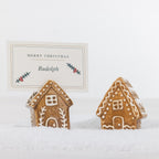 Two gingerbread-style ceramic house name card holders displayed in snow, with one holding a personalised Merry Christmas place card.