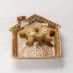 Gingerbread house-shaped ceramic trinket plate filled with two decorated gingerbread biscuits.
