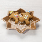 Star-shaped gingerbread-style ceramic trinket plate holding two decorated gingerbread biscuits.