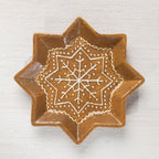 Top view of a star-shaped ceramic trinket plate with a detailed white snowflake design.
