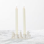 White ceramic two-candle holder featuring festive Santa, Christmas tree and reindeer figures on a snowy background.