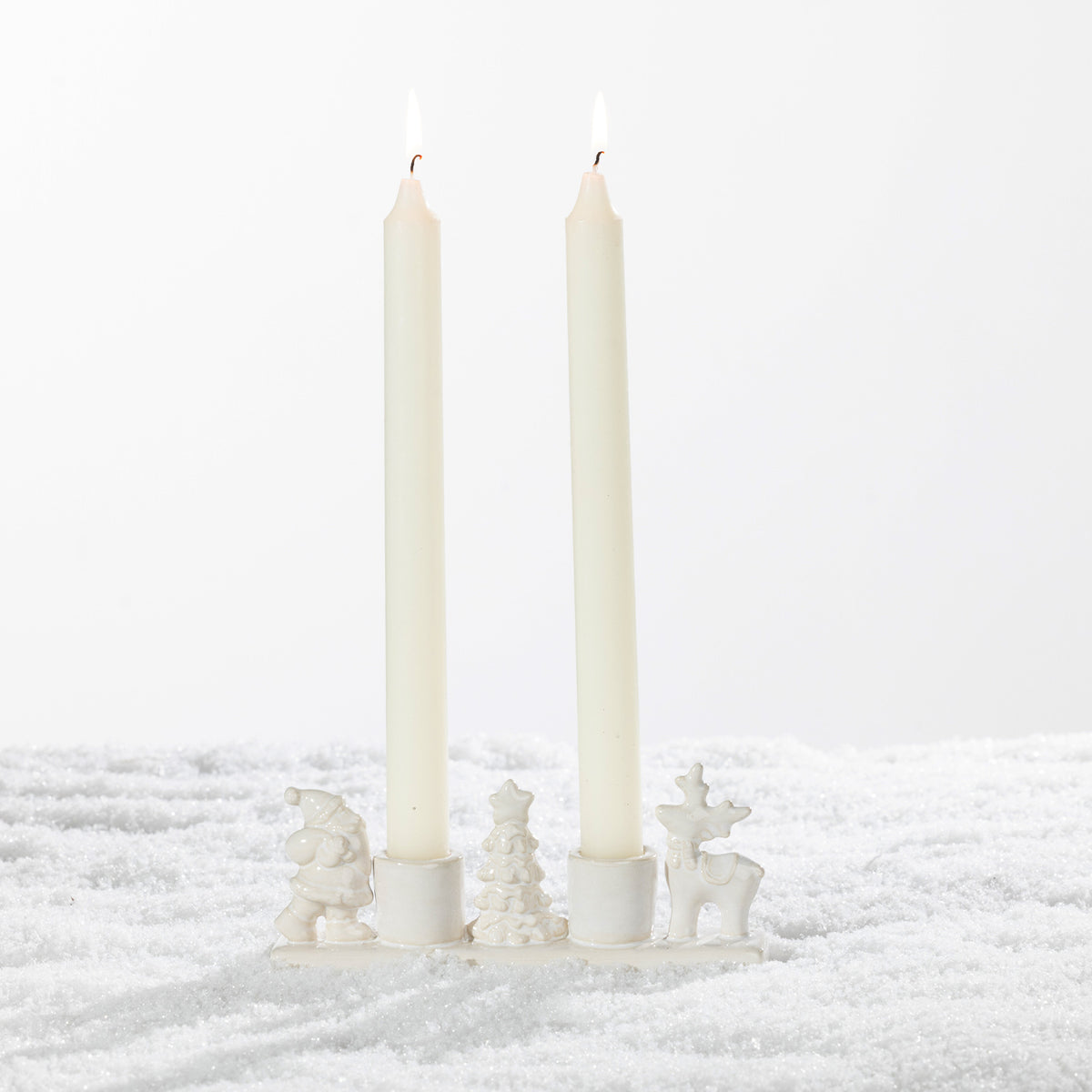 White ceramic two-candle holder featuring festive Santa, Christmas tree and reindeer figures on a snowy background.