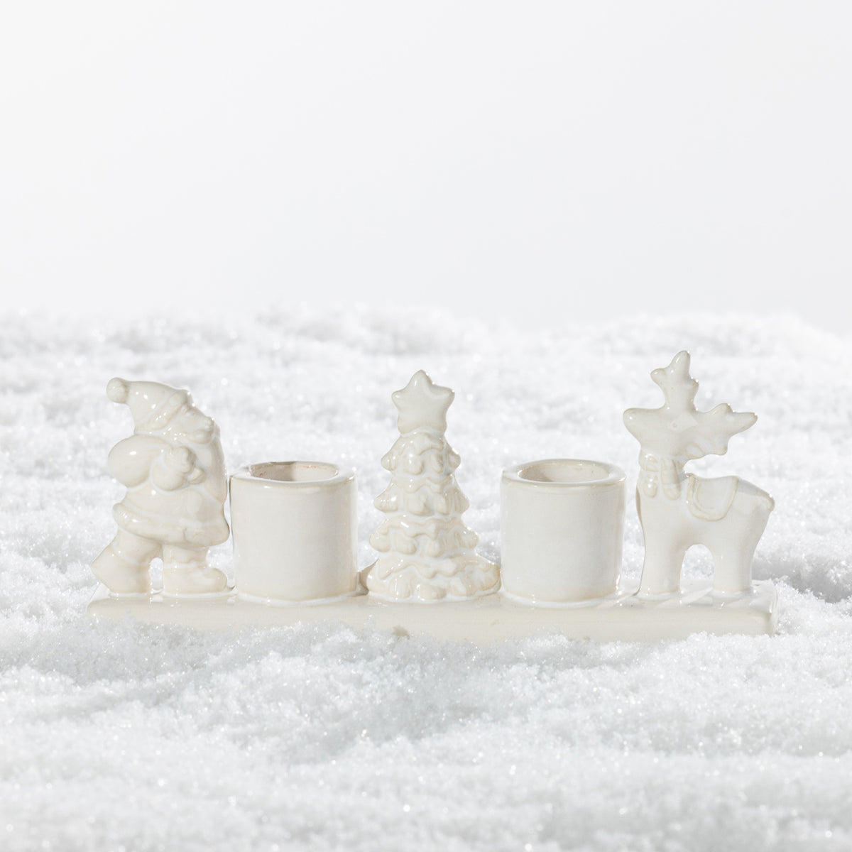 White ceramic two-candle holder featuring festive Santa, Christmas tree and reindeer figures on a snowy background.