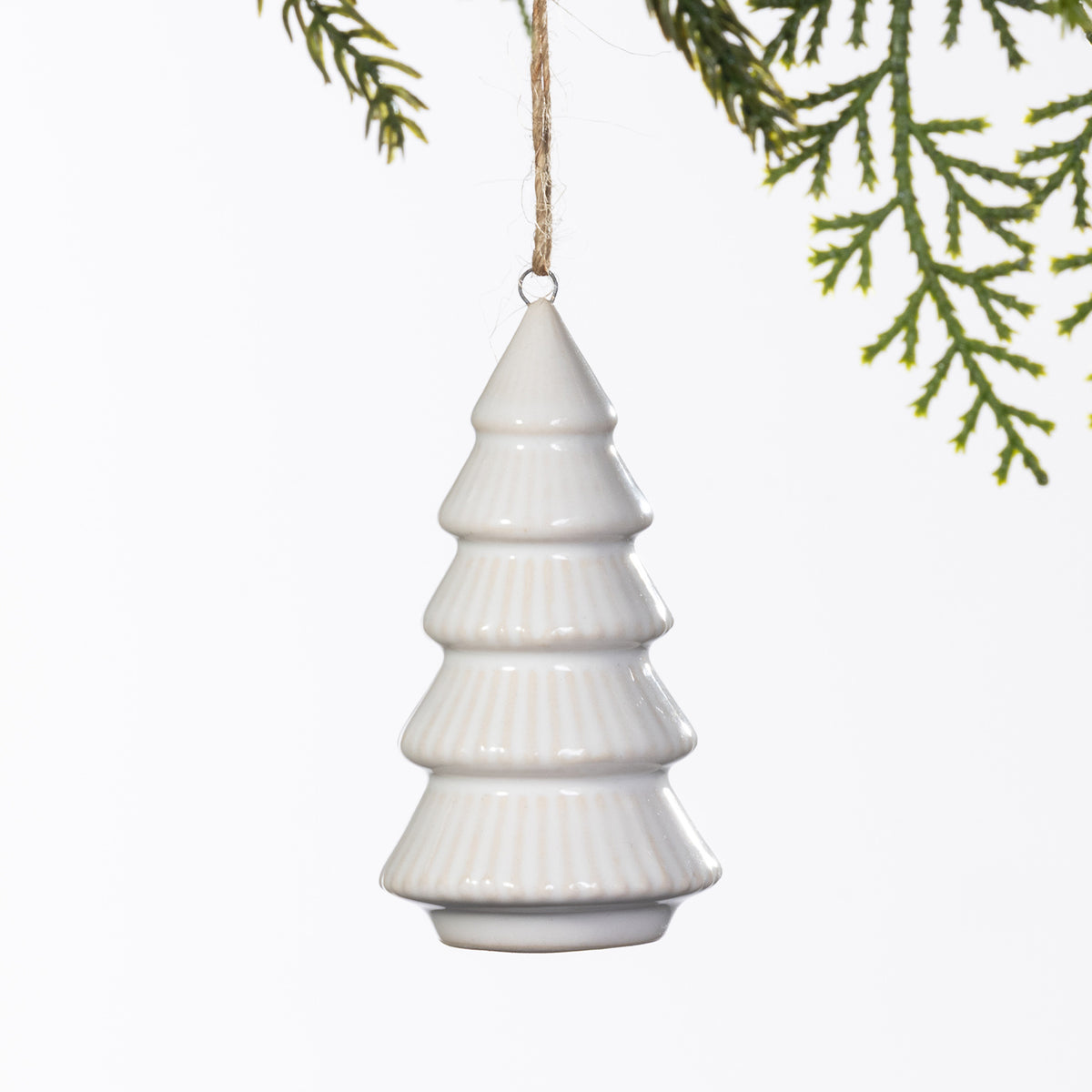 White ceramic Christmas tree hanging decoration with a tiered design and subtle ribbed detailing, suspended from a natural twine loop.