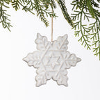 White ceramic snowflake hanging decoration with embossed snowflake detailing, suspended from a natural twine loop.