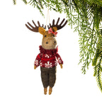 A felted wool Christmas ornament shaped like a moose hanging from a pine branch. The moose wears a red and white knit sweater, dark brown pants, and a red-and-white bow on its head, against a white background.