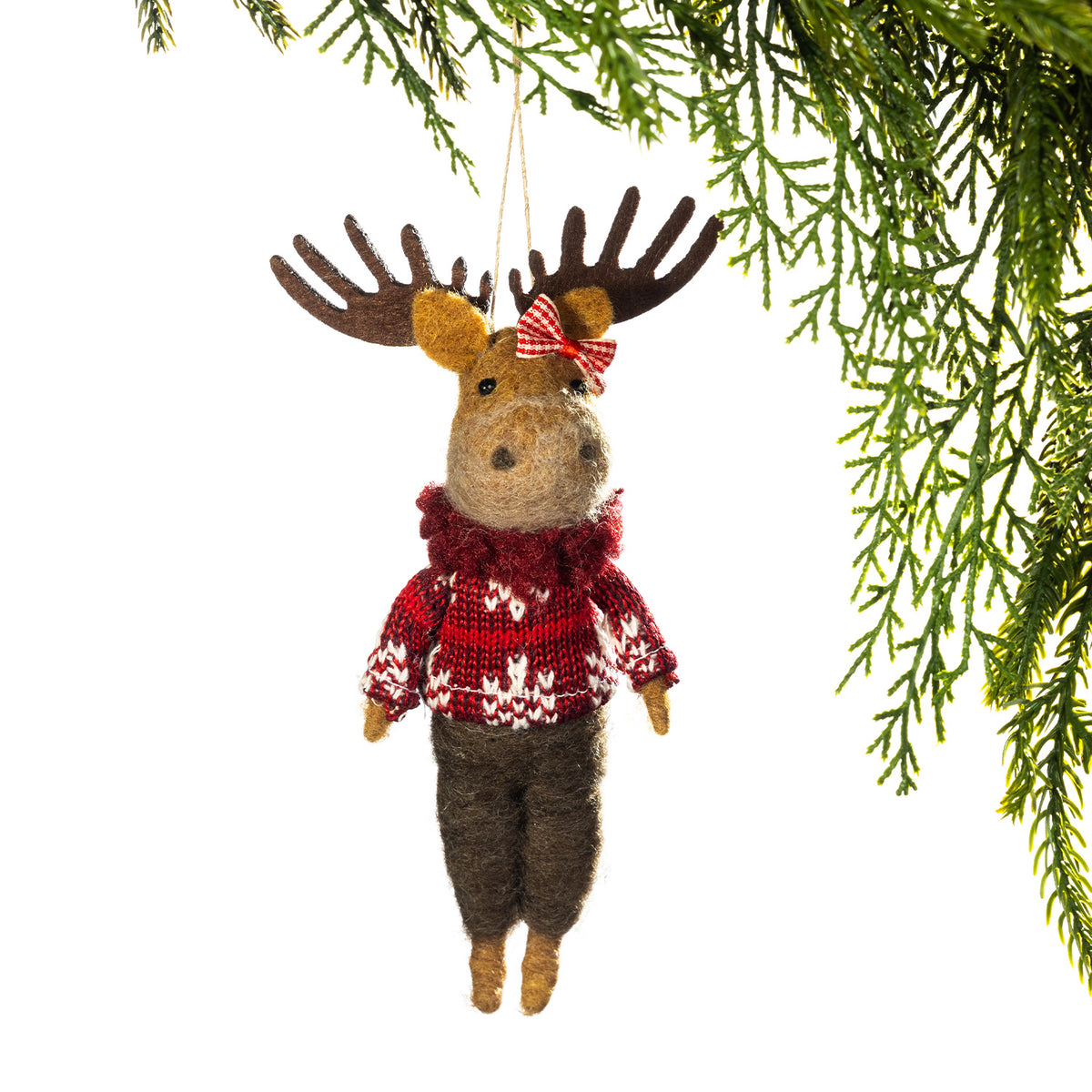 A felted wool Christmas ornament shaped like a moose hanging from a pine branch. The moose wears a red and white knit sweater, dark brown pants, and a red-and-white bow on its head, against a white background.