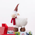 A Christmas sheep figurine standing on presents. 