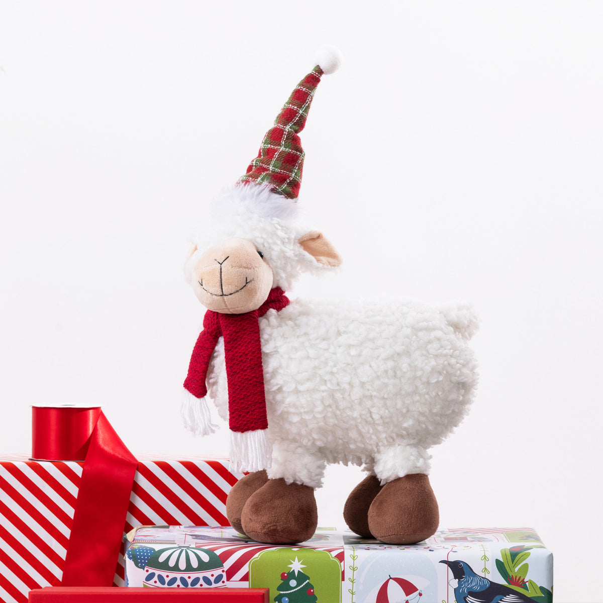 A Christmas sheep figurine standing on presents. 