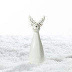 Small white ceramic Christmas reindeer decoration with a smiling face, gold detailing and a tapered body, standing on a snowy surface.