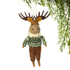 A felted wool moose ornament hanging from a pine branch against a white background. The moose has brown antlers, a brown face and legs, tan ears and hooves, and wears a green and white patterned sweater with a white faux-fur neck.