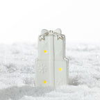 Small white ceramic stacked Christmas presents LED decoration featuring a gold-trimmed bow, embossed snowflakes and warm glowing lights on a snowy surface.