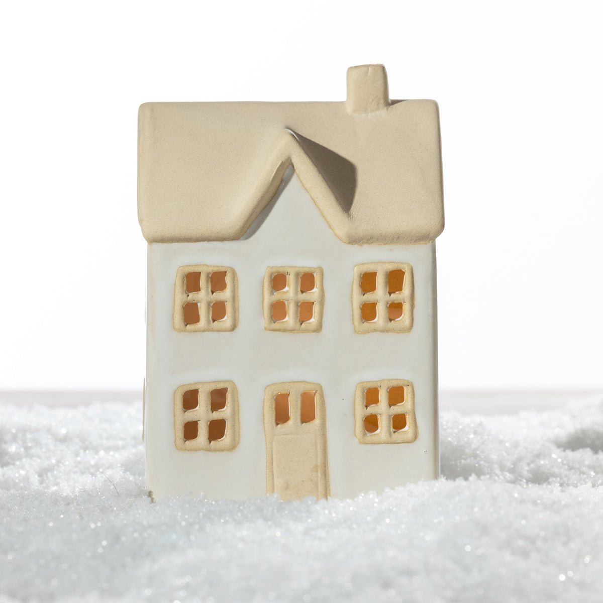 Large white ceramic Christmas house with a natural sand-coloured roof, chimney, two-storey design and detailed windows, displayed on a snowy surface.