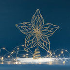 Christmas Wishes gold glitter star tree topper with an intricate openwork design and spiral base, displayed with warm festive lights.