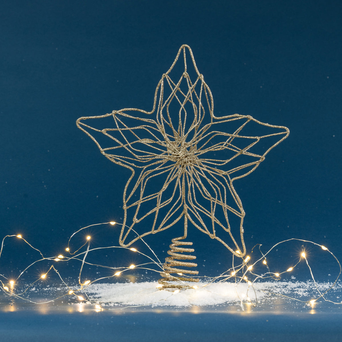 Christmas Wishes gold glitter star tree topper with an intricate openwork design and spiral base, displayed with warm festive lights.