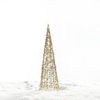 Christmas Wishes gold cone tree LED décor with an open woven design and warm white lights, displayed in a snowy setting.
