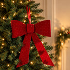 Christmas Wishes red velvet present bow with sparkling dot details, displayed on a Christmas tree with warm white lights.