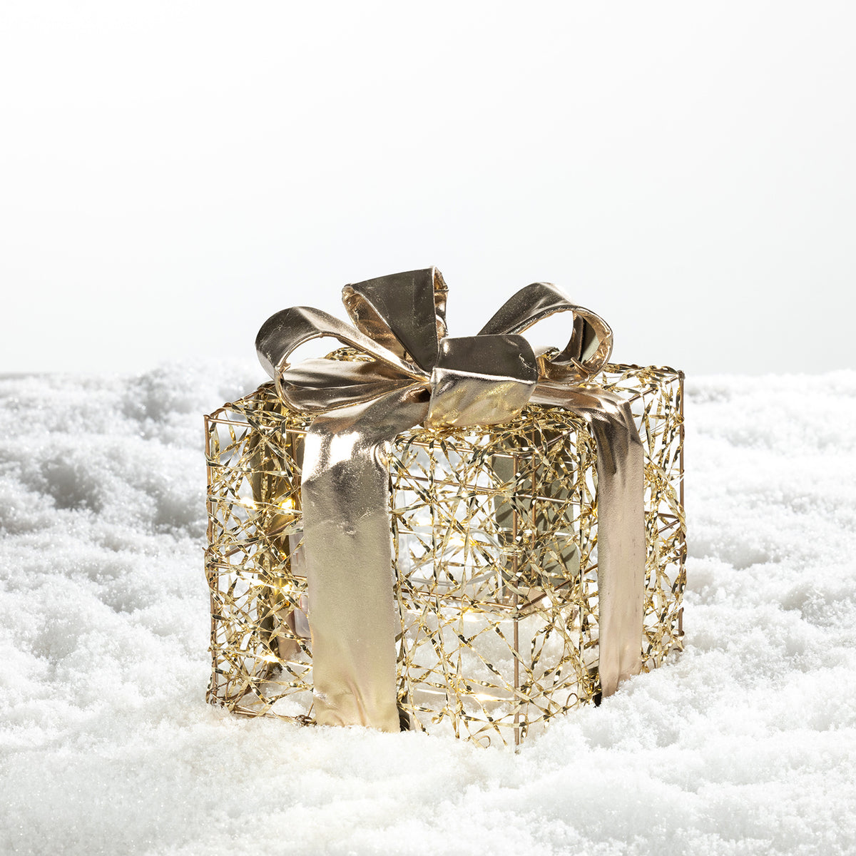 Christmas Wishes gold present box LED decoration with an open wire design and metallic gold bow, displayed on a snowy background.