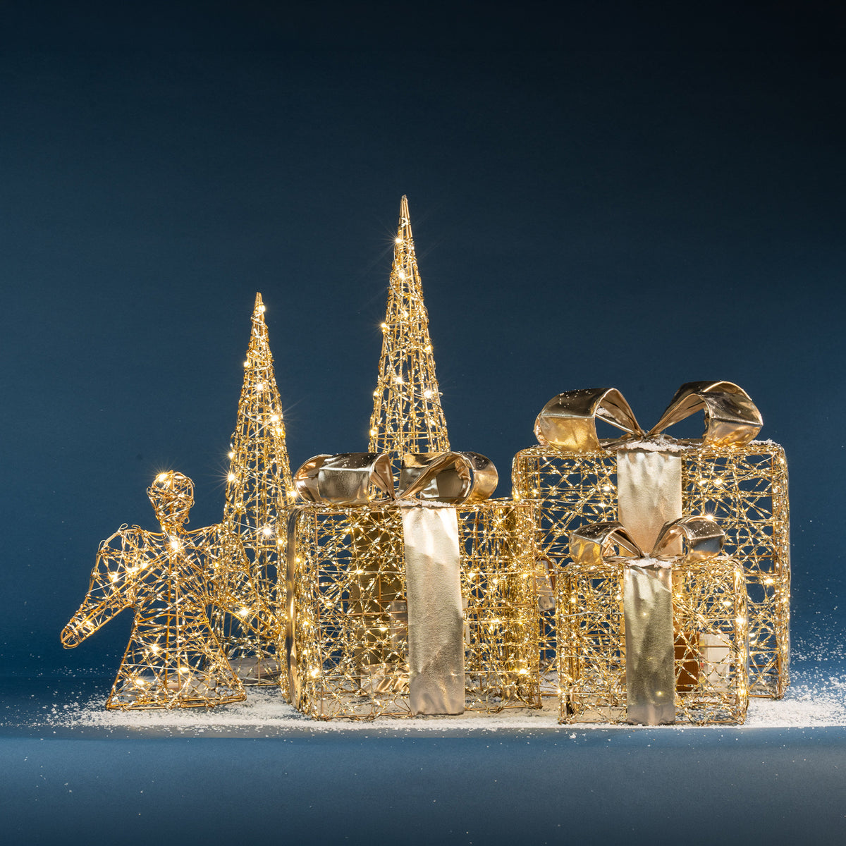 Christmas Wishes gold present box LED decorations displayed with coordinating illuminated Christmas trees and angel décor against a deep blue backdrop.